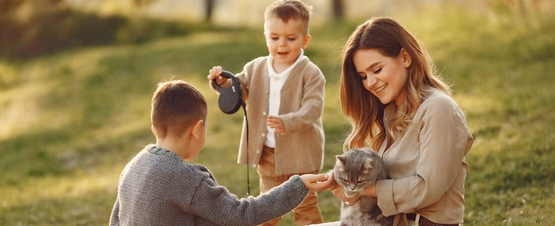 Una madre y dos niños jugando con un gato.