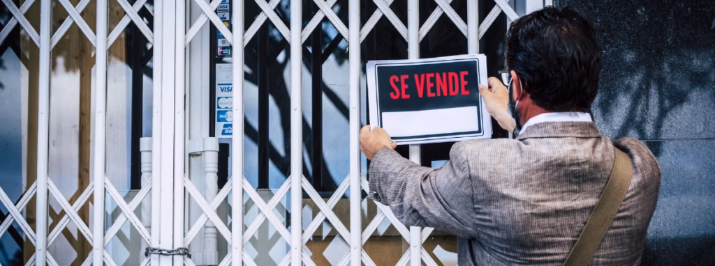 Persona colgando un cartel de se vende en un negocio 